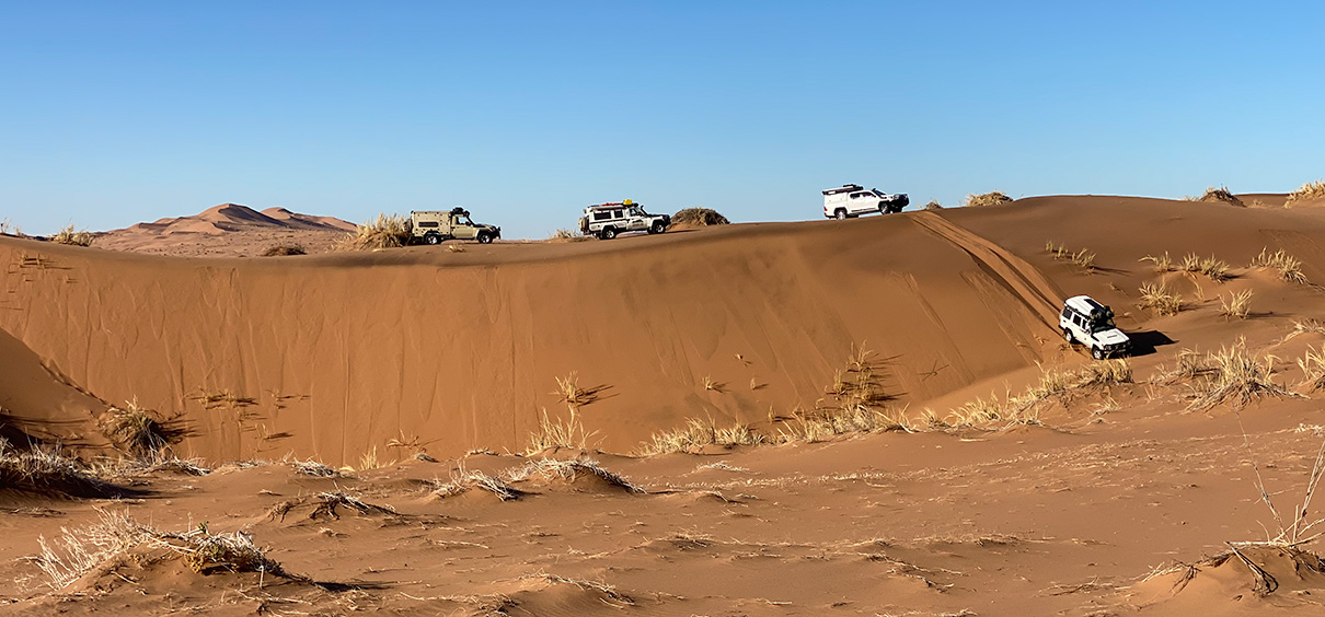 view of vehicles driving down the slipface of a dune
